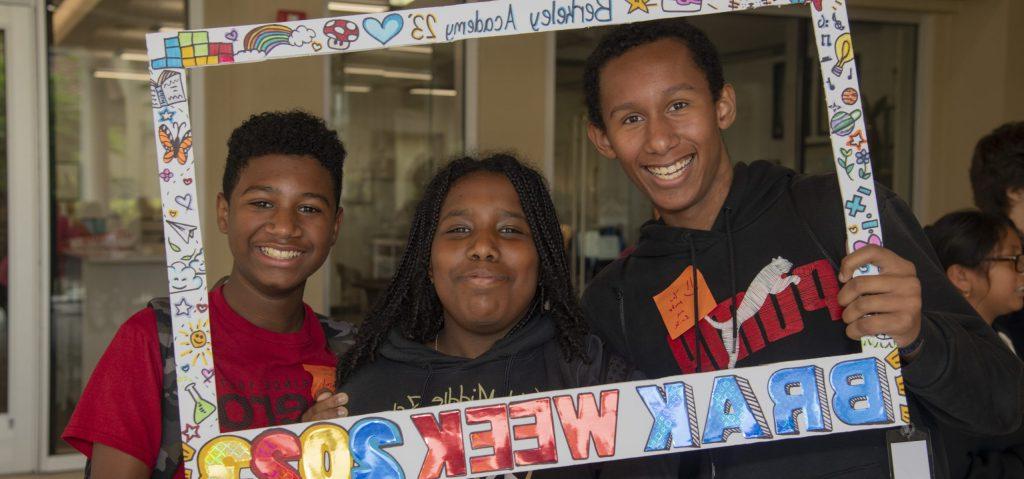 berkeley academy three students holding up a frame over their faces, private school